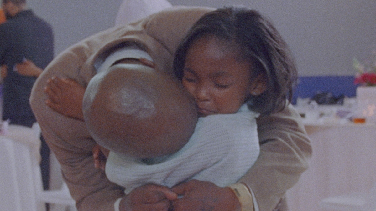 Two Black people are embracing in a close hug.