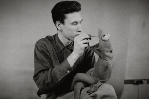 Black and white image of Jim Henson with a Kermit puppet.