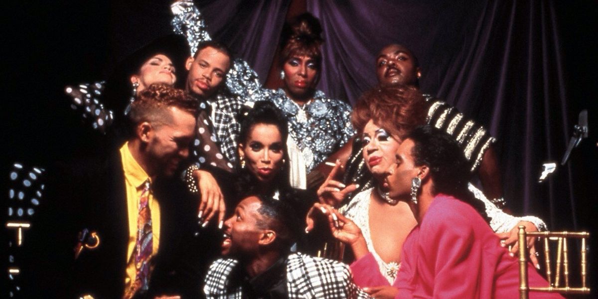 Subjects of the movie Paris is Burning, posing for the camera. They are all in glamorous makeup and fashion and colorful clothing.