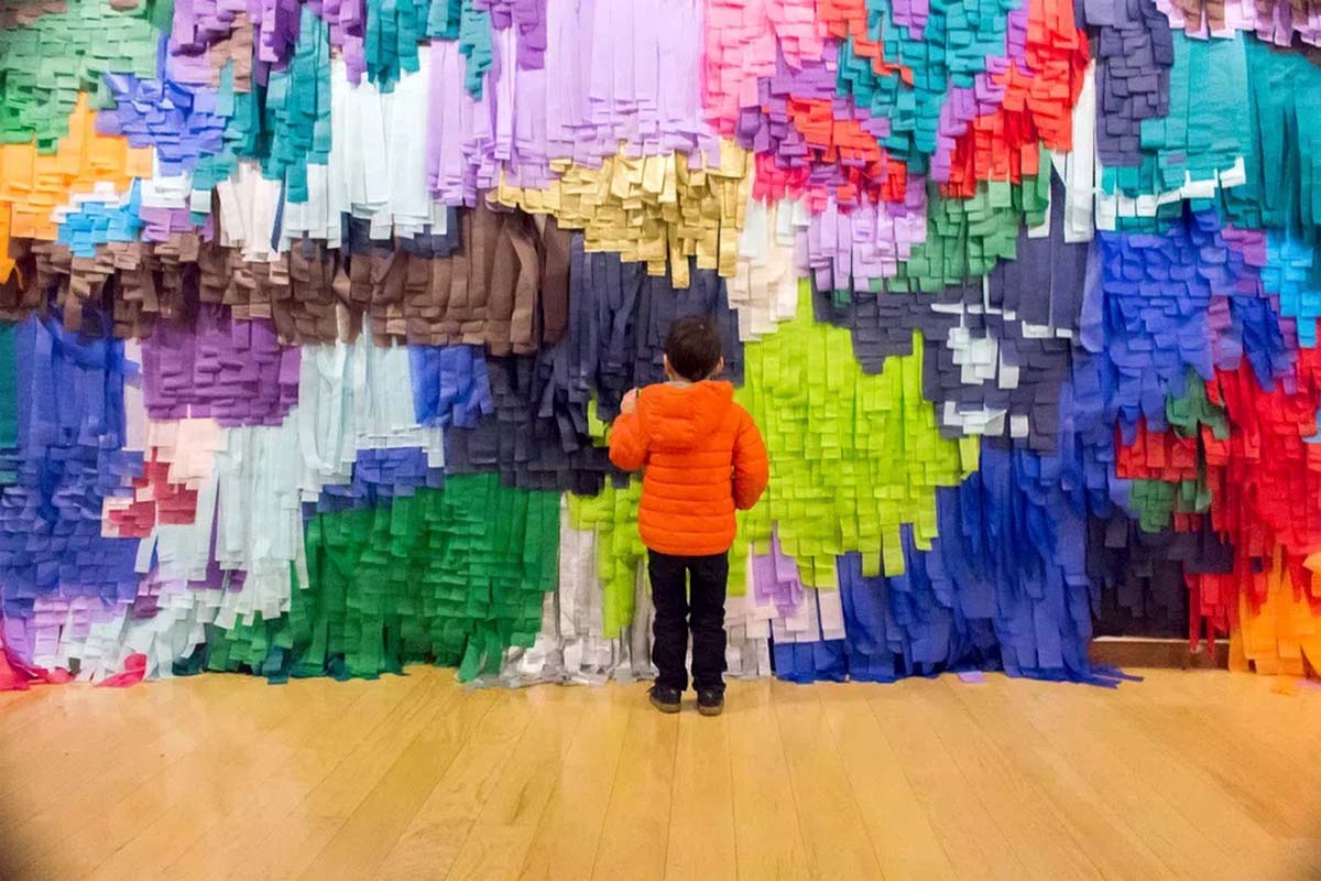 A child stands in front of artist Aves Aras’ multi-colored art installation made of paper and glue. From Craig and Brent Renaud’s ‘State of the Art.’ Photo by Thomas Willis. Courtesy of PBS.
