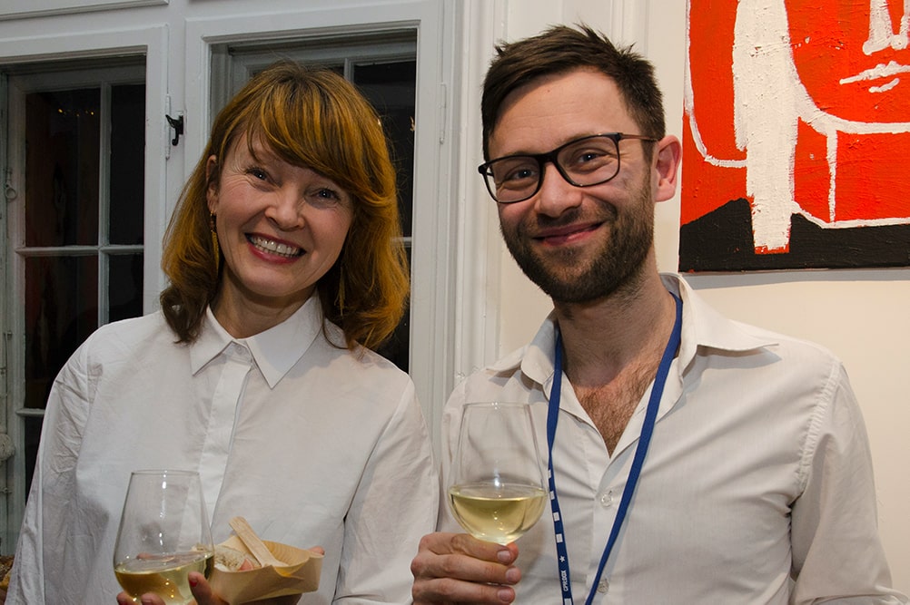 Tine Fischer, a white woman with shoulder-length dirty-blond hair in a white shirt with Niklas Engstrøm, a white man with brown hair, beard, and black frame glasses. He is also wearing a white shirt. Courtesy of CPH:DOX.