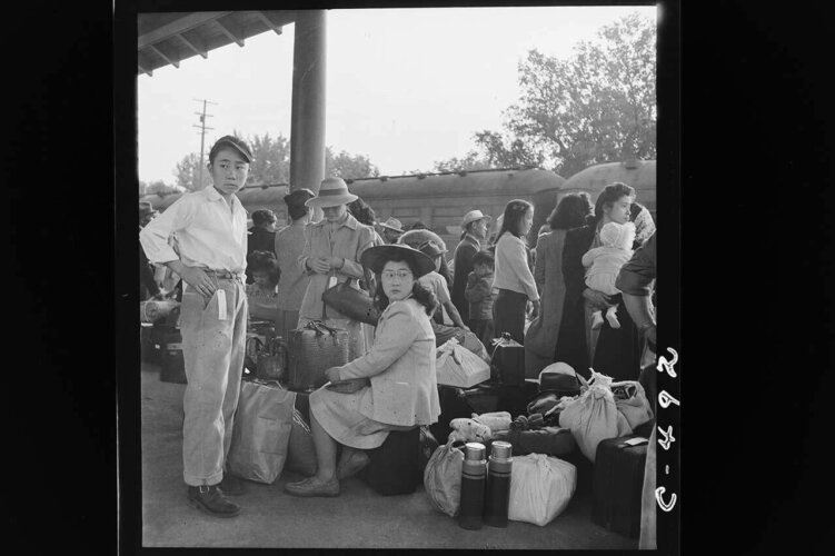Archival photo of a Japanese family as they await a train that will take them to an internment camp. From Ken Burns’ ‘The U.S. and the Holocaust.’ Photo by Dorothea Lange. Image courtesy of PBS. 