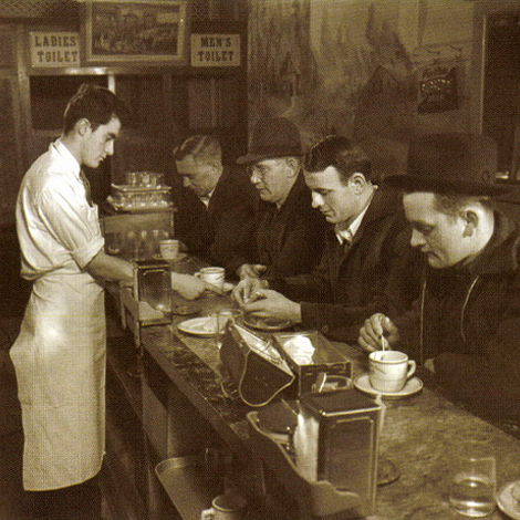 Adult men are sitting at the counter of a diner