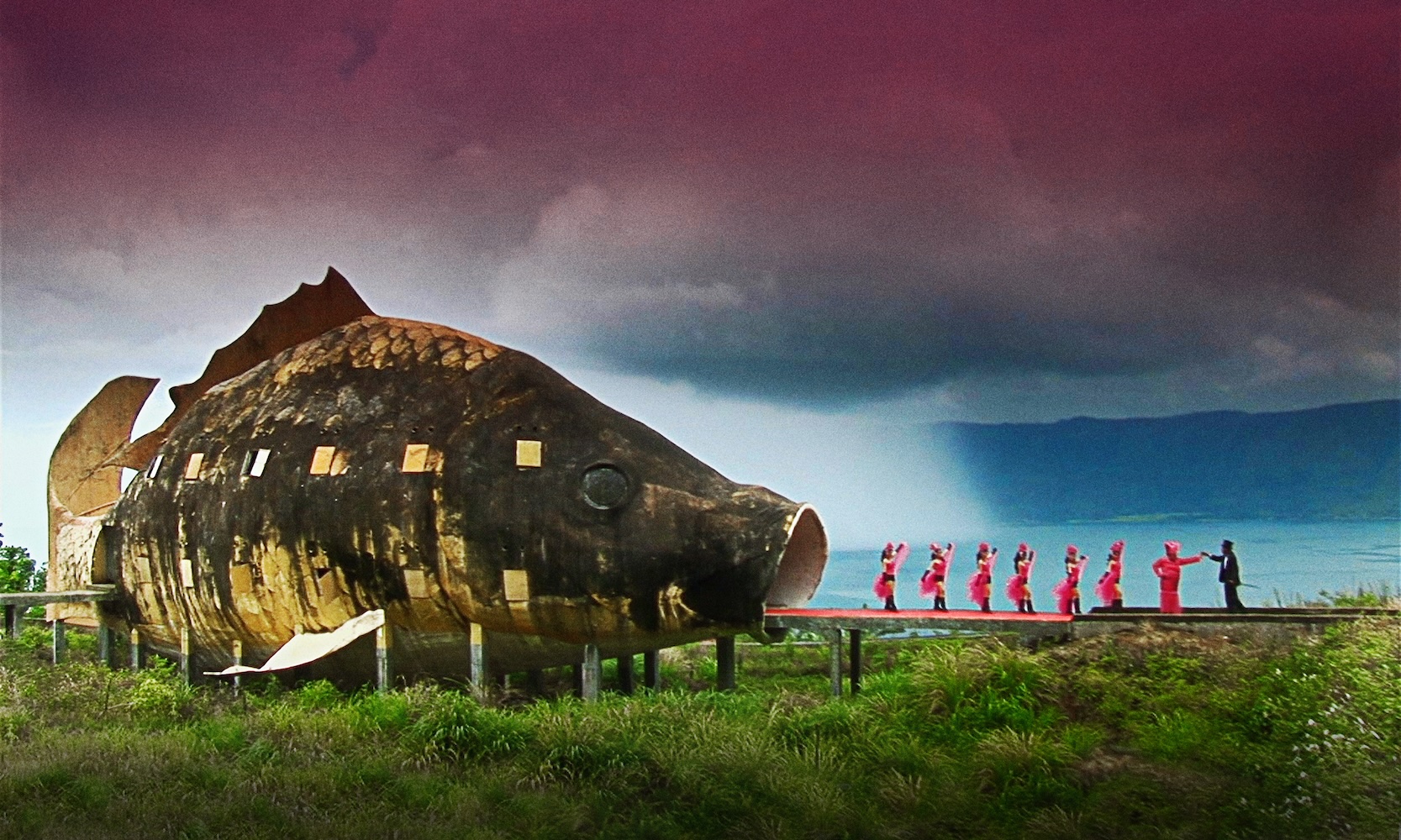 A group of colorful dancers strut out of a giant fish's mouth.