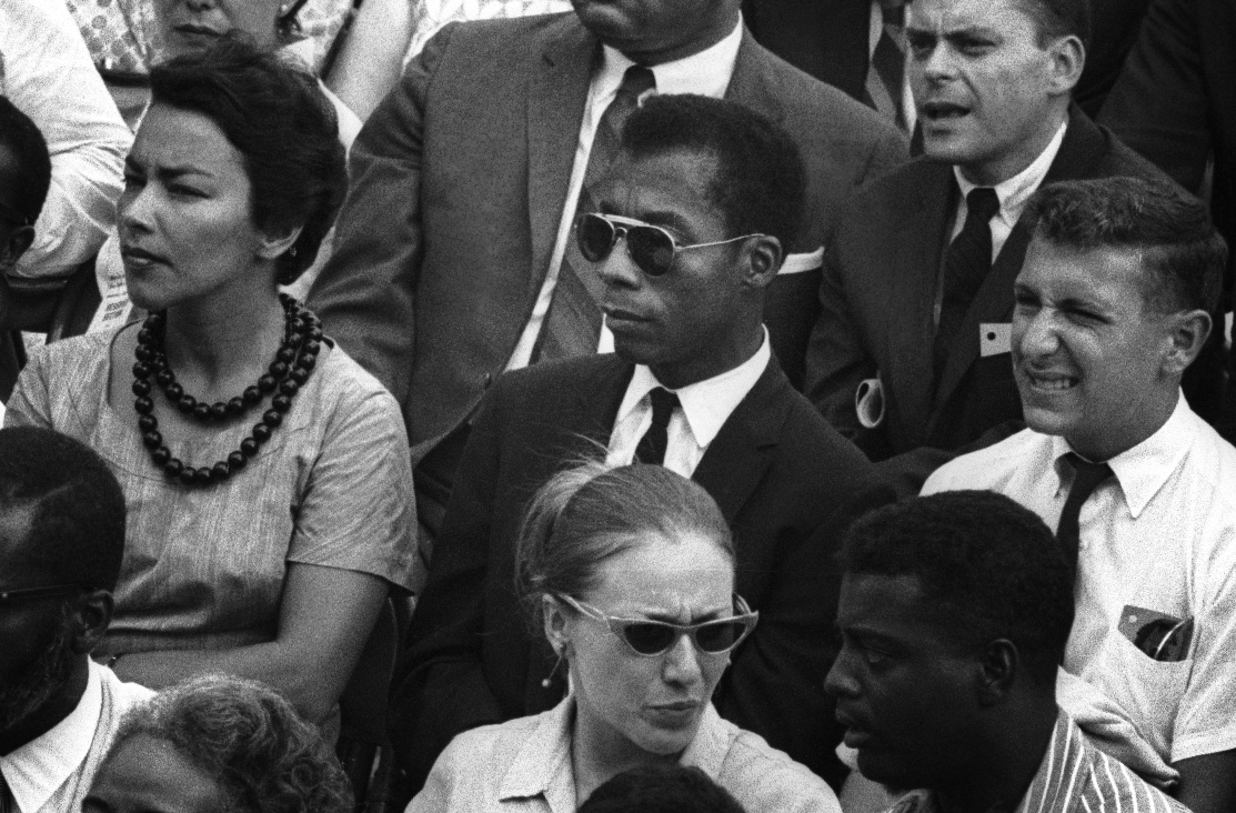 Black and white still of James Baldwin in a crowd.