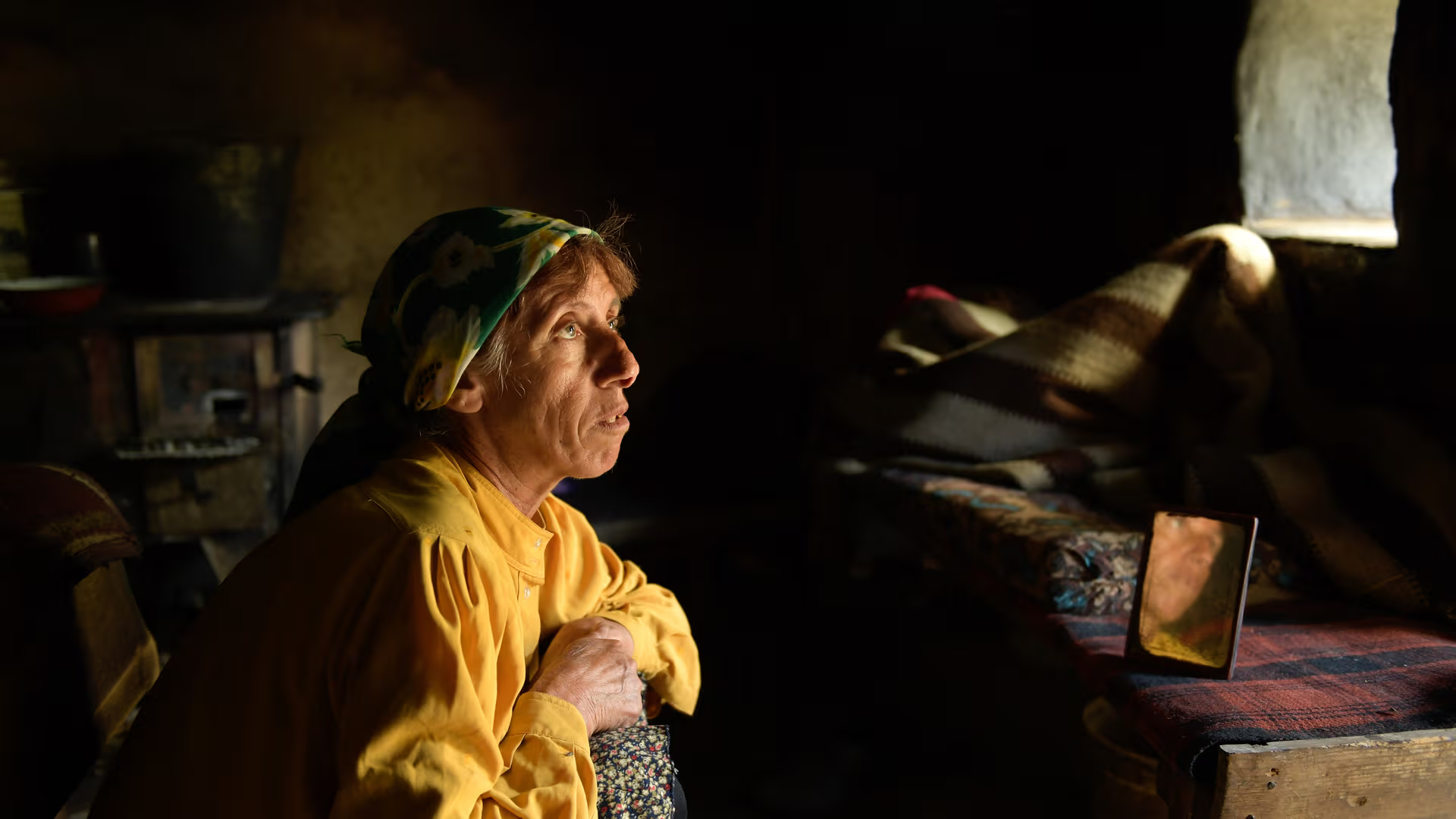 A woman in a scarf looks out a window.