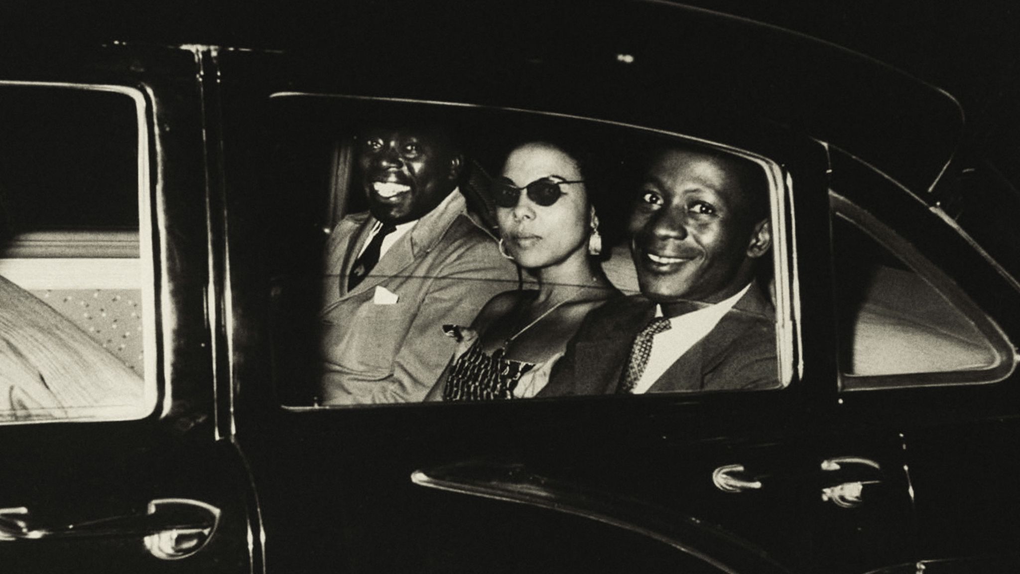 Three people look out from a car.
