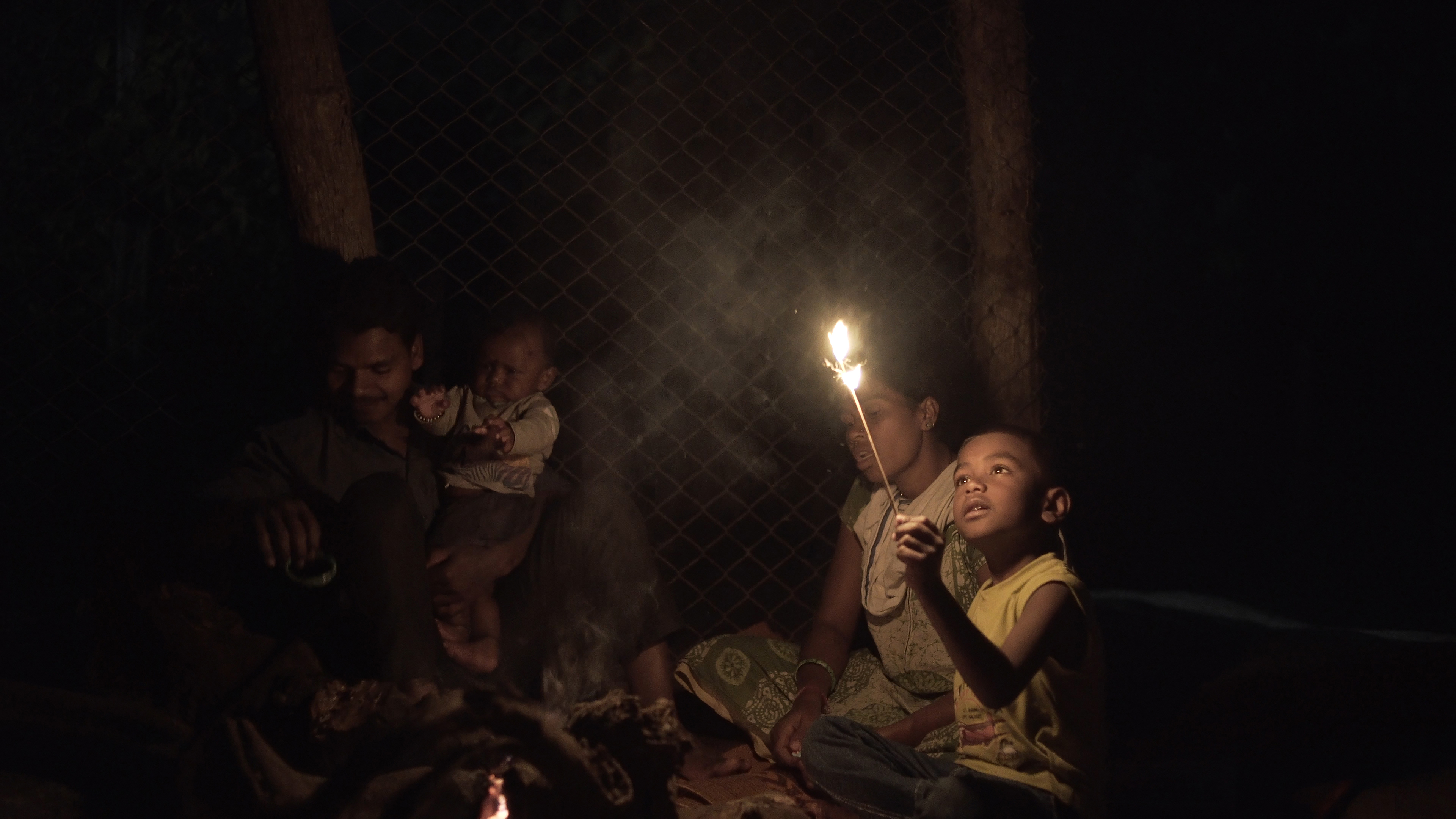 A young boy holds up a lit candle.