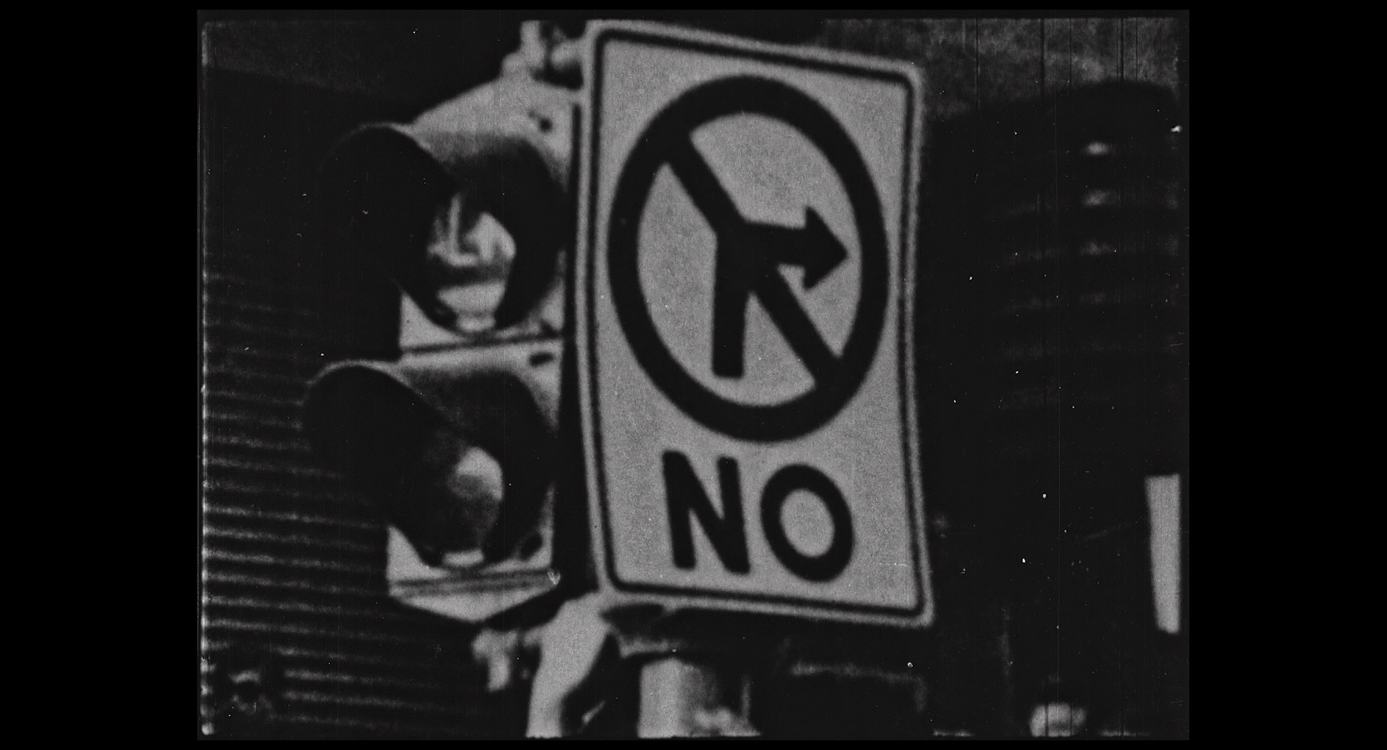 A black and white image of a traffic light and a "no right turn" sign.