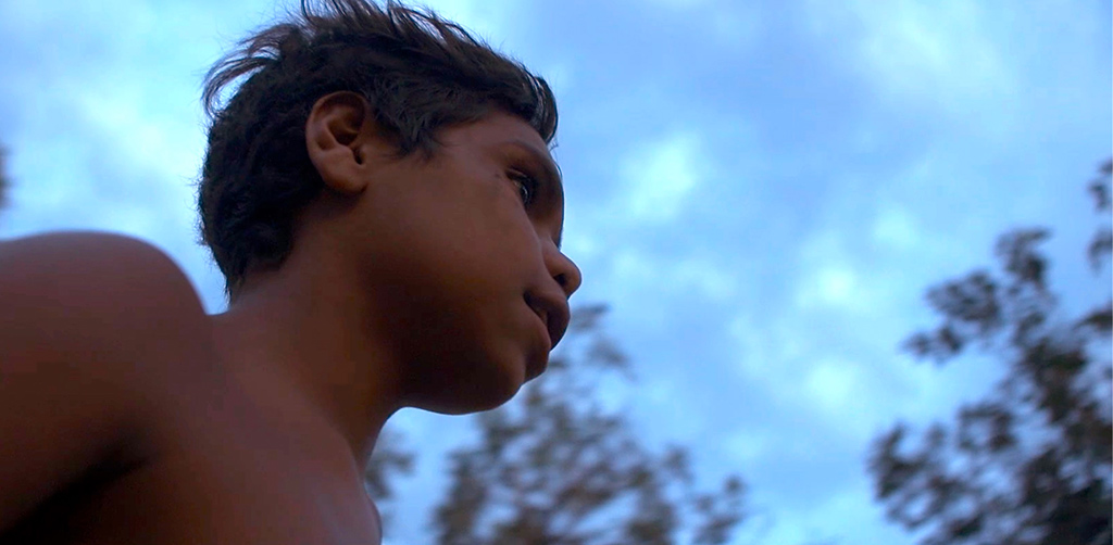 Profile of a young boy against a blue sky