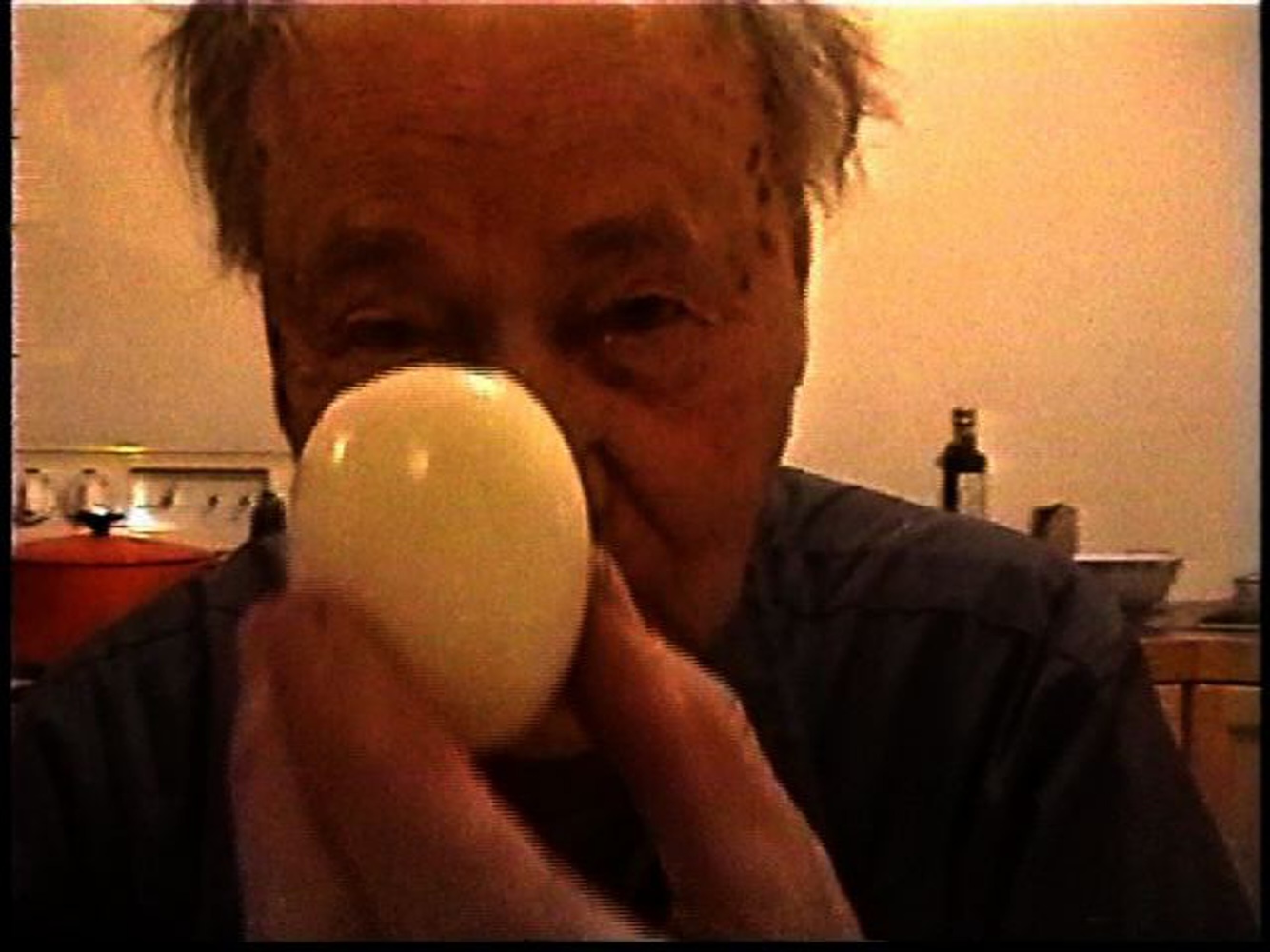 Jonas Mekas holds an egg up to the camera.