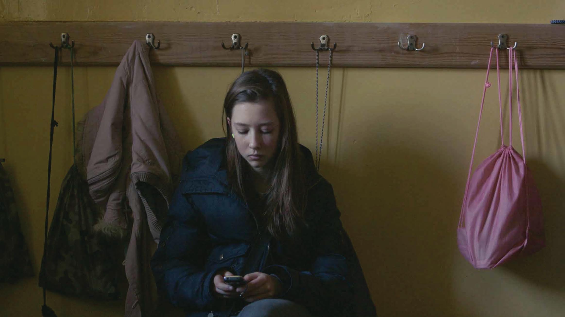 A teenaged girl looks at her cell phone.
