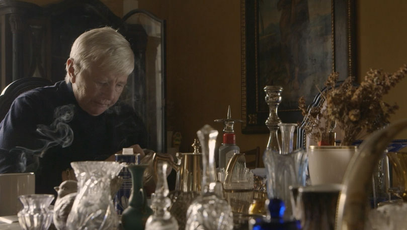 An figure behind a collection of glassware.
