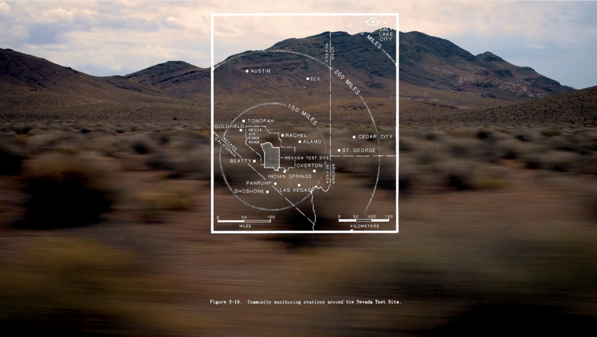 A transparent map of southern Nevada overlays an image of a desert ridge, partly covered in vegetation, partly barren. The foreground of the image is filled with motion blurred bushes, as captured from a moving vehicle. The map shows the outline of the Nevada Test Site, nested within the boundaries of the Nellis Airforce Base, northwest of Las Vegas. Three concentric circles delineate 100 mile intervals emanating from the Test Site. Map caption “community monitoring stations around the Nevada Test Site.”
