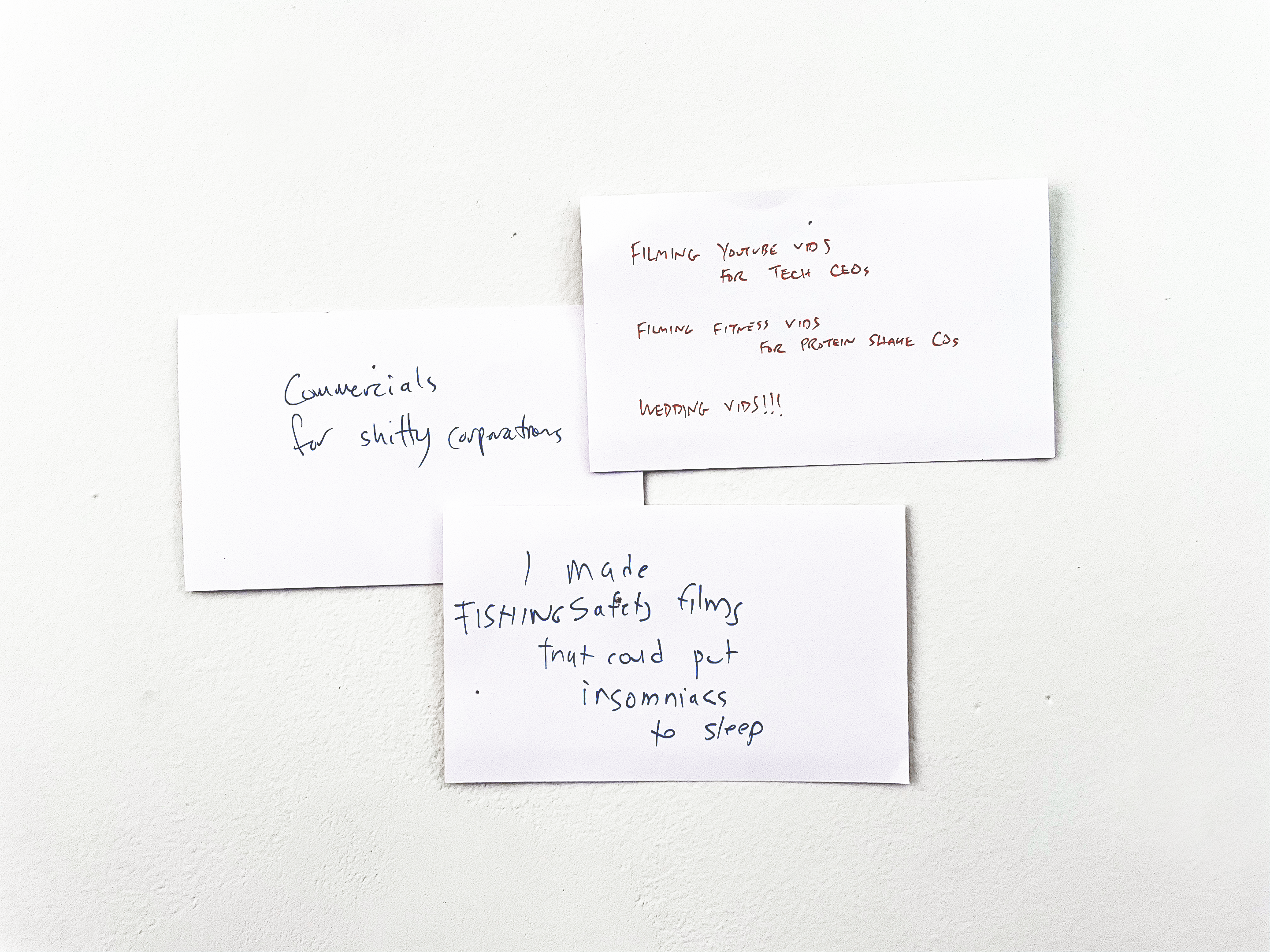 Three white notecards with black writing, pinned to a white wall.