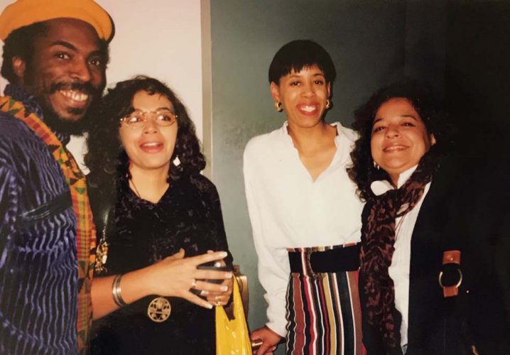 A photo of three young black women and a black man, all smiling at the camera