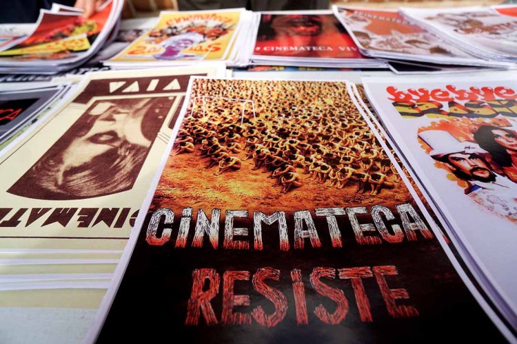 A table of posters designed by the workers of Cinemateca Brasileira that support their resistance. The one in the foreground says “Cinemateca Resiste.” Photo by Benedito Faga / Alamy Stock Photo.