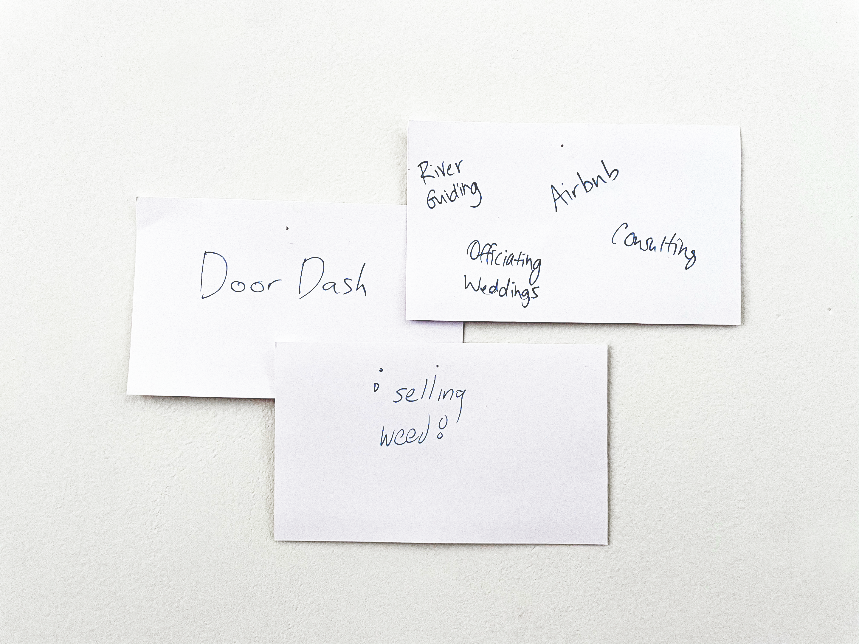 Three white notecards with black writing, pinned to a white wall.