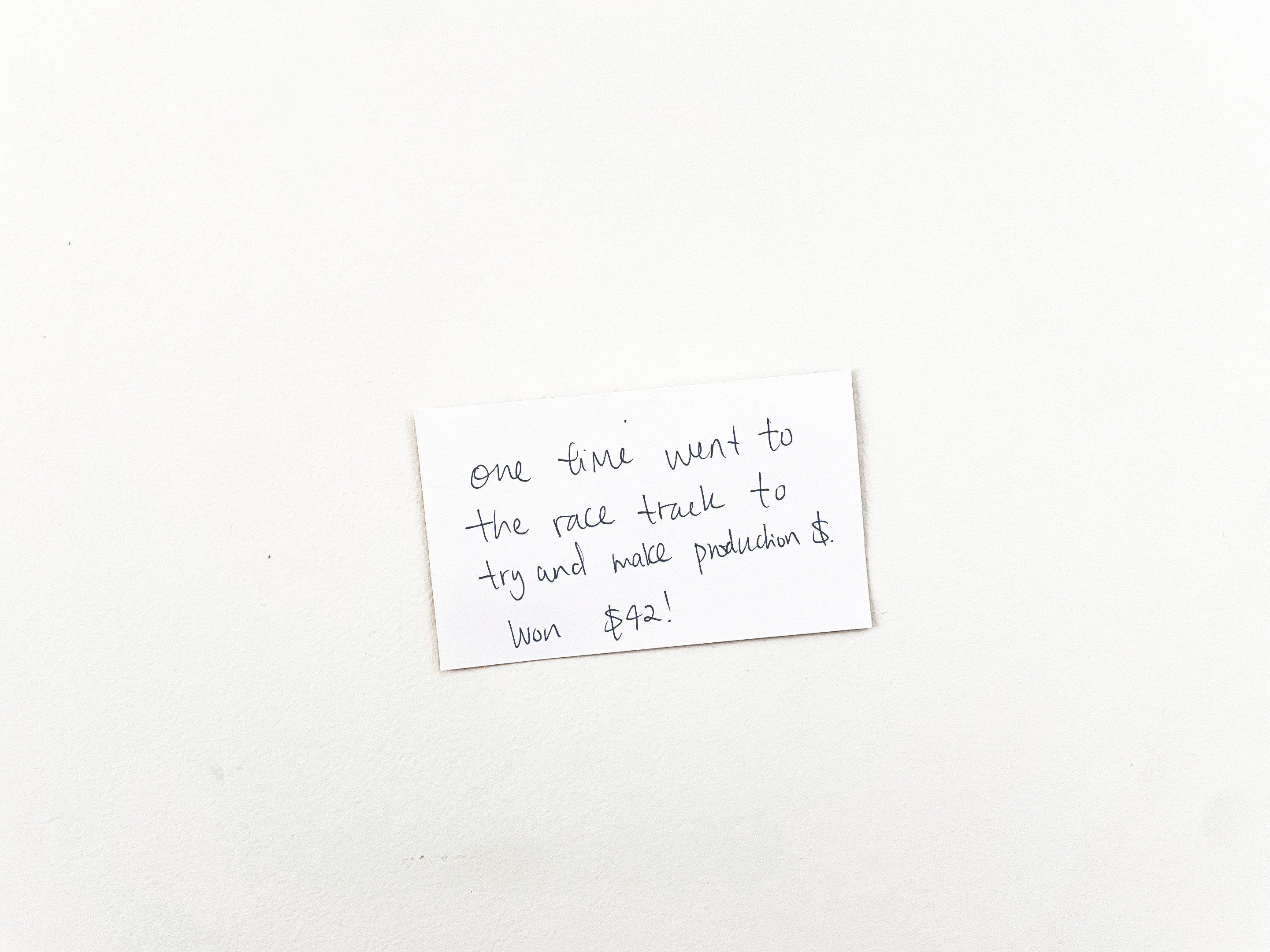 Single white notecard with black text pinned to a wall.