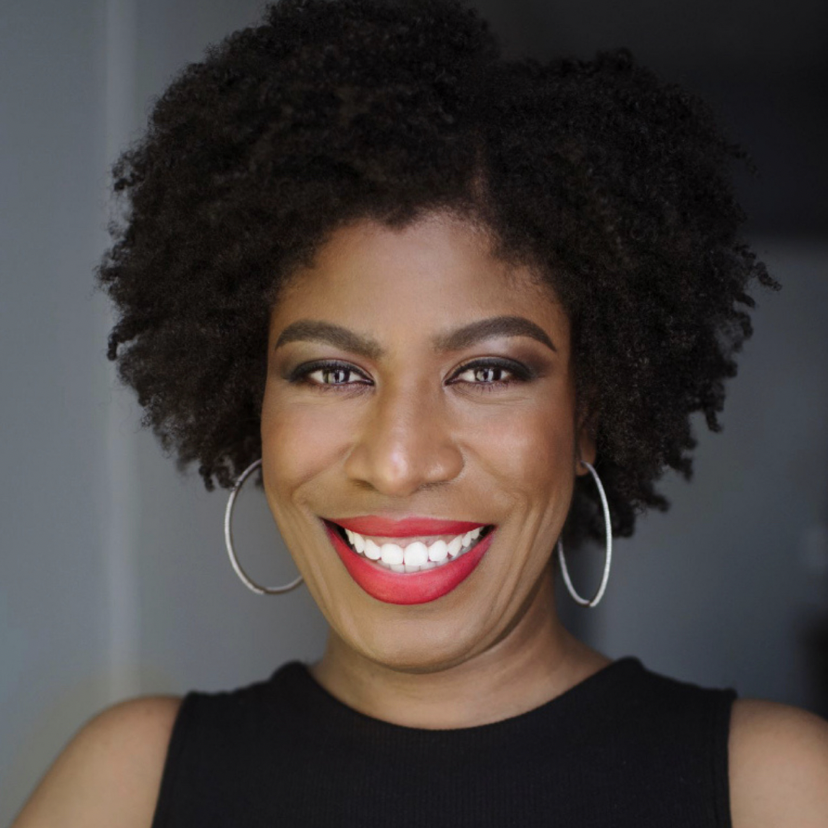 Stacie McClam is a Black woman with short, curly hair wearing a black shirt with red lipstick and large, silver hoop earrings.