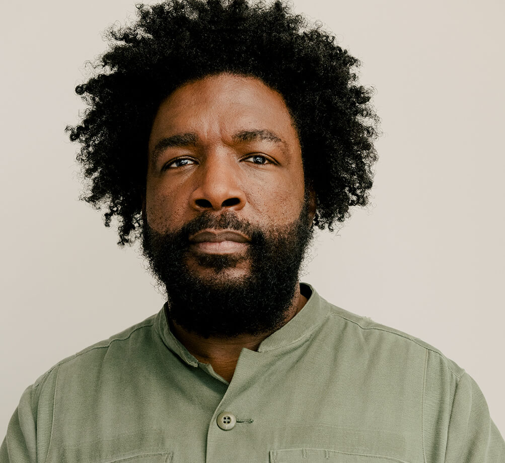 Filmmaker Ahmir "Questlove" Thompson, a Black man with a beard and a short afro, wearing a khaki shirt. Courtesy of Searchlight Pictures.