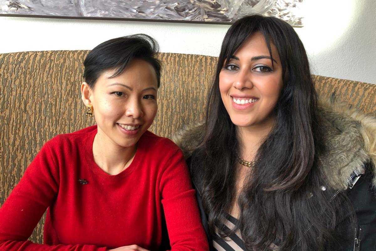 Poh Si Teng is an Asian woman of Malaysian Chinese origin with shoulder-length black hair.  She is sitting with Smriti Mundhra, a South Asian filmmaker with long black hair. They’re both smiling at the camera. Photo courtesy of Poh Si Teng. 