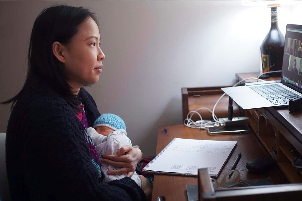 Poh Si Teng, an Asian American woman with black hair, holding her three-day-old baby Navin, as she takes a Zoom meeting. Courtesy of Poh Si Teng.