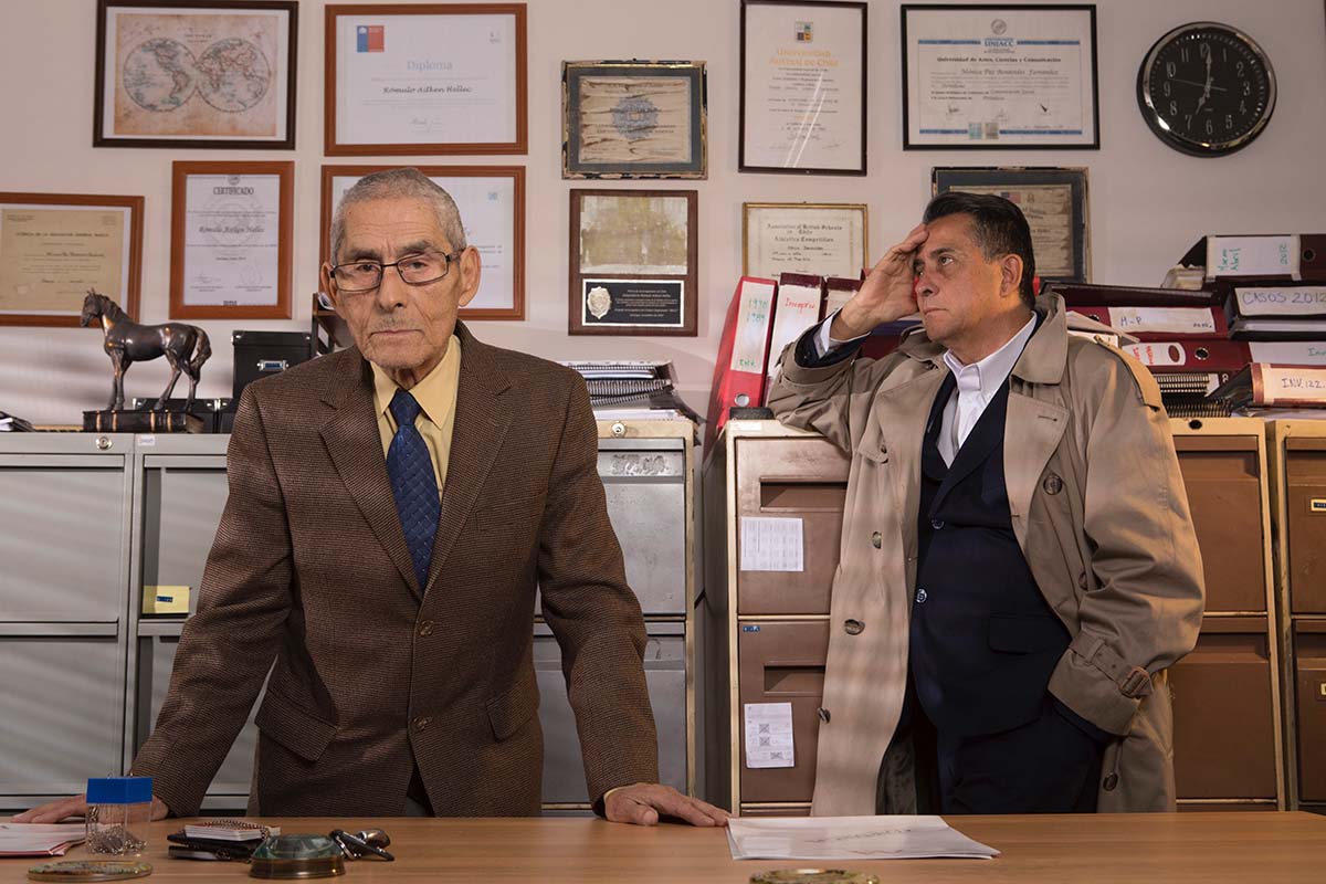 Sergio Chamy, an elderly Chilean man, left, and private detective Romulo Aitken, right, standing against a wall of framed certificates. From Maite Alberdi’s Academy Award-nominated  ‘The Mole Agent.’ Courtesy of Gravitas Ventures.