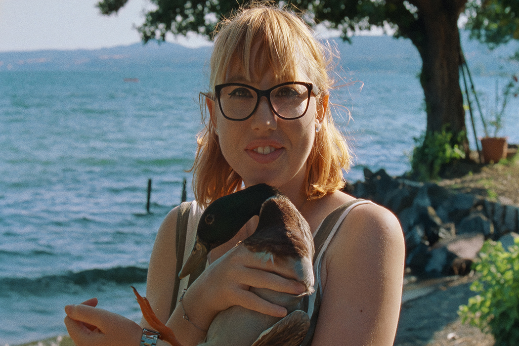 A young Italian woman with blonde hair and glasses, holding her pet duck. From Pietro Marcello, Francesco Munzi and Alice Rohrwacher’s ‘Futura.’ Courtesy of NYFF. 
