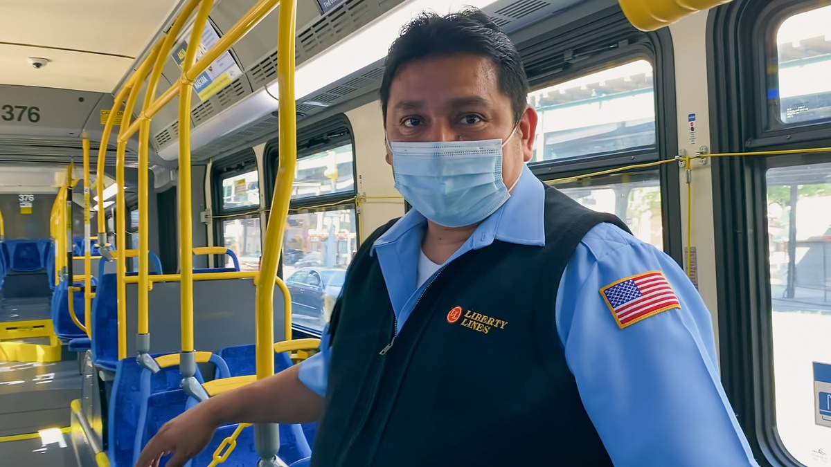 Arlet Guillpa's fatrher, Carlos Guillpa, at his job as a bus driver in New York City. He is wearing his work uniform, as well as a protective mask, and he is standing in his bus. From 'COVID Diaries NYC.' Courtesy of HBO