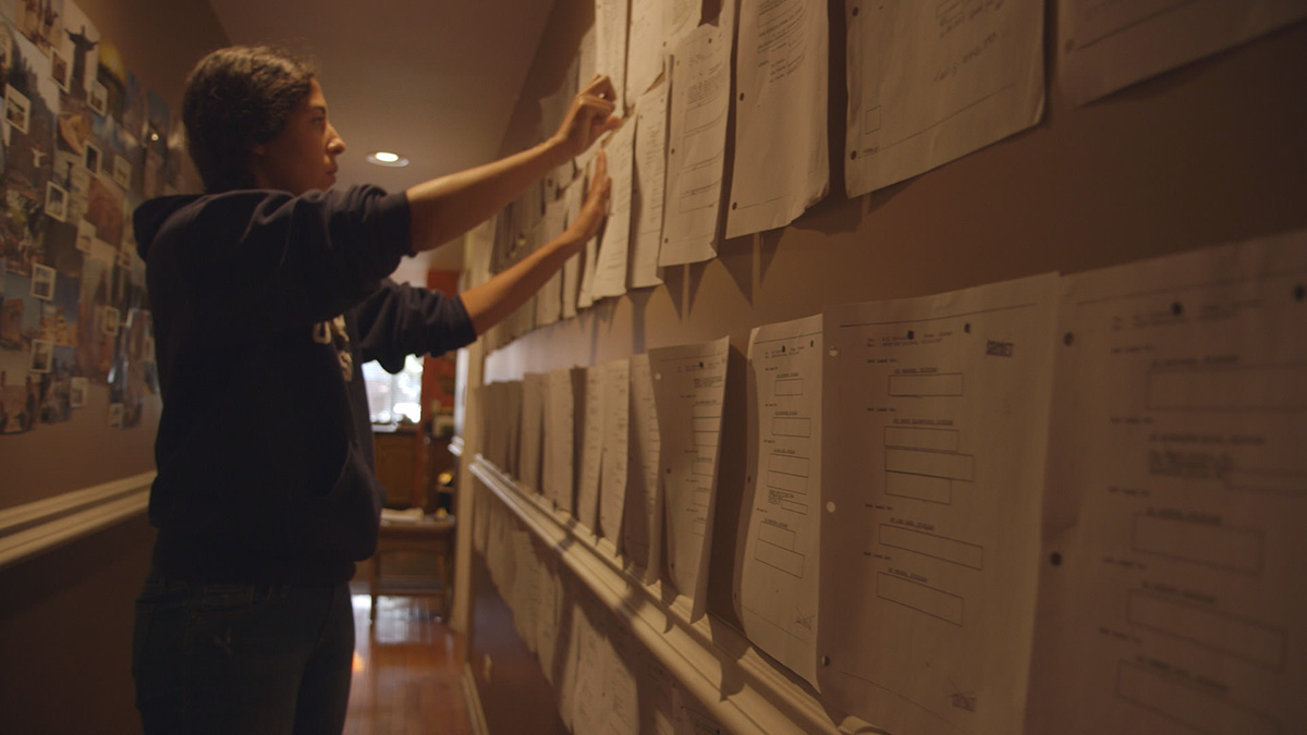 Filmmaker Assia Boundaoui is an Algerian-American woman, seen here pinning FBI documents onto a board. From Boundaoui’s ‘The Feeling of Being Watched.’ Courtesy of Multitude Films.