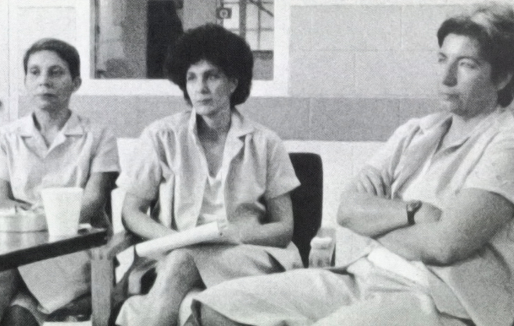 Three women sit looking to the left of the frame; in the foreground a woman sits with her arms crossed. Left to right: Alejandrina Torres, Susan Rosenberg, Silvia Baraldini. 