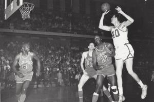 Black and white image of Scranton Miners center Bill Spivey, a 7'2" white man wearing a white jersey with the number 40 on it, shooting a basketball during a game against the Allentown Jets