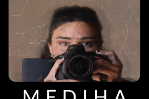 film poster for 'Mediha.' Black and brown background with white text. Image of a person holding up a video camera. 