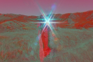 A film still with holographic colors shows a figure in a field.