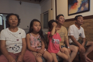 Still image from 'Beyond Utopia,' showing five members of a North Korean family sitting on a couch.