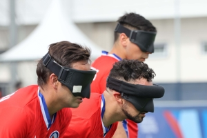 Three Chilean soccer players -  wearing black out masks and red shirts -  prepare for play at the Parapan American Games in 2023.
