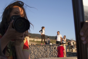 Through a reflected mirror, Kirsten Johnson holds a camera up to her face.
