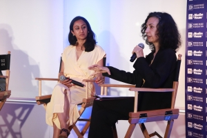 Two women sit on director's chairs.