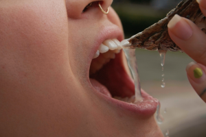 An extreme close up of an oyster dripping succulent juices into an open mouth. 