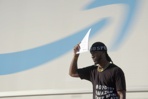 black man shades his face with a paper in front of an amazon logo