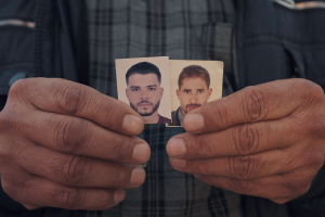 hands hold two small pictures of young men side by side 