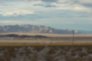 Wide landscape of a desert with a mountain in the background and a light blue sky. 