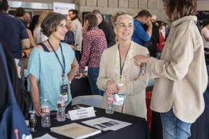 Three women talk to each other around a table with an "Archival Producers Alliance" sign.