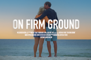 A couple faces the ocean in an embrace, the man holding his wife and kissing her head. The title "ON FIRM GROUND" over the image.