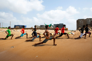 A group of men doing lunges on the beach