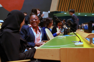 Two international high school delegates share a candid moment of laughter inside the United Nations General Assembly Hall during the WFUNA International Model United Nations conference. Surrounded by the iconic setting of global diplomacy, the image captures the intersection of youth, leadership, friendship, and cross-cultural connection that defines The Delegates.
