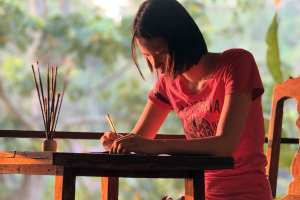 Teenage girl sits at table making art