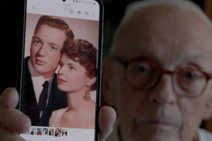 Man shows us a photo of two young lovers on his phone.