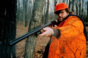 Michael Moore in orange, holding a rifle
